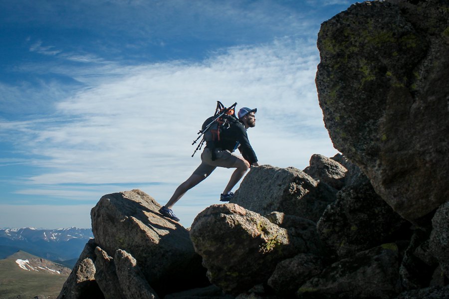 Climber scrambling up large boulders under a blue sky