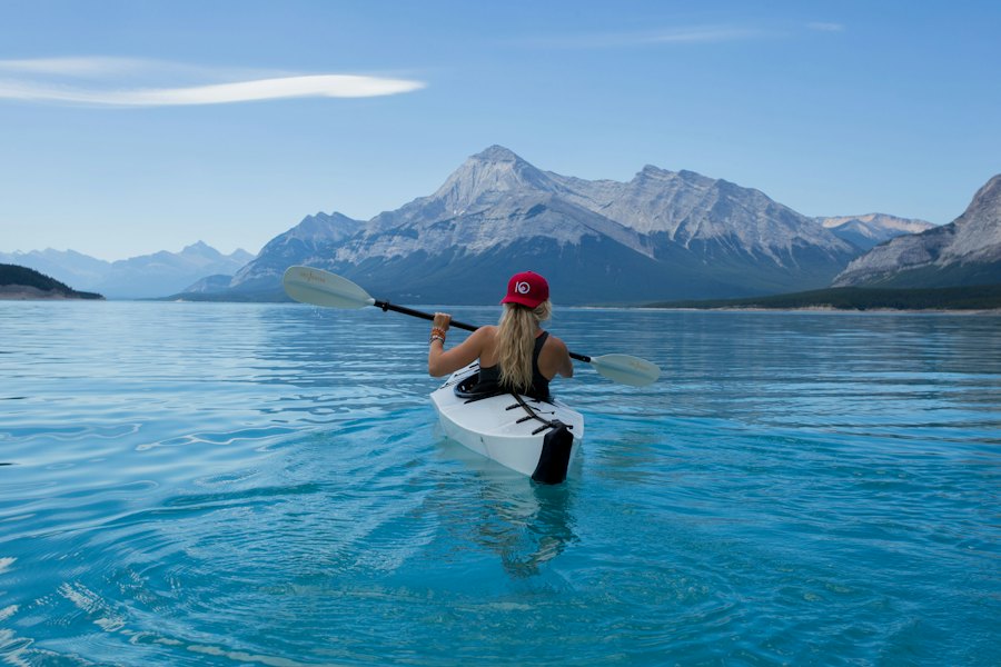 Person paddling a kayak on a turquoise mountain lake